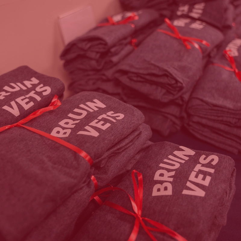 Veterans Week 2024 shirts stacked with a red ribbon on a table