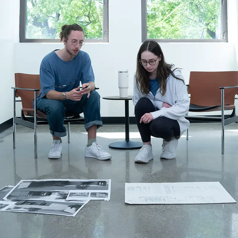 a male and female student looking over plans