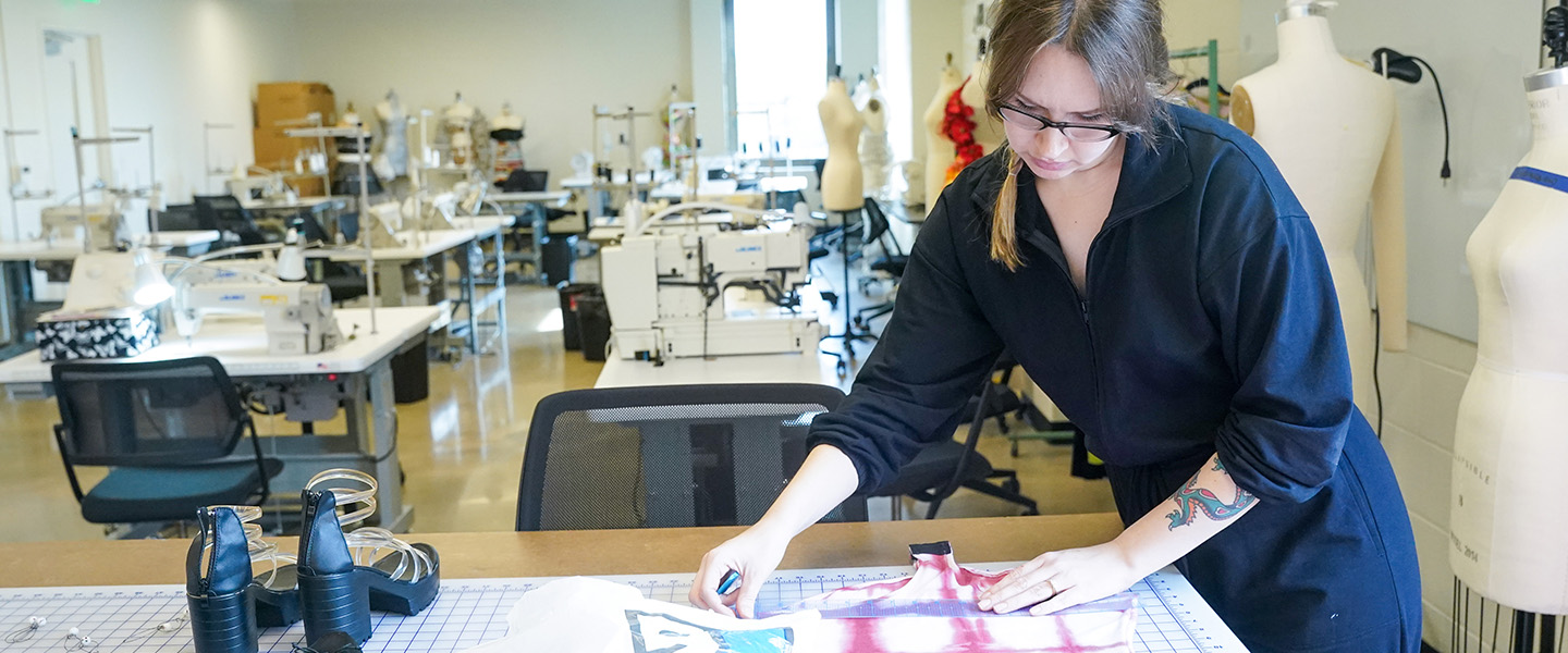 A female student works on a garment using her sewing machine.