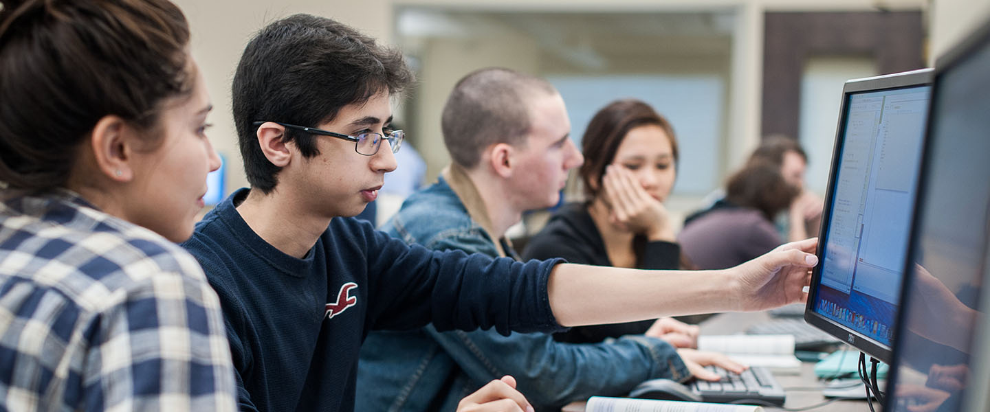 Four students working at a computer in a lab