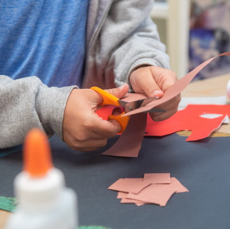 Close up of student cutting construction paper