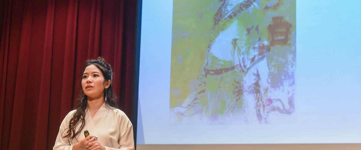 Dr. Melody Li speaks to Belmont studies with slideshow in background. 