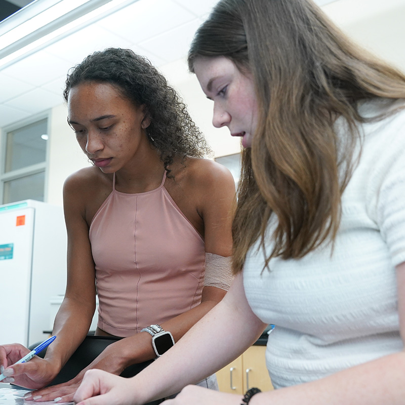 alumna Nya Sabe working in a science lab with another student