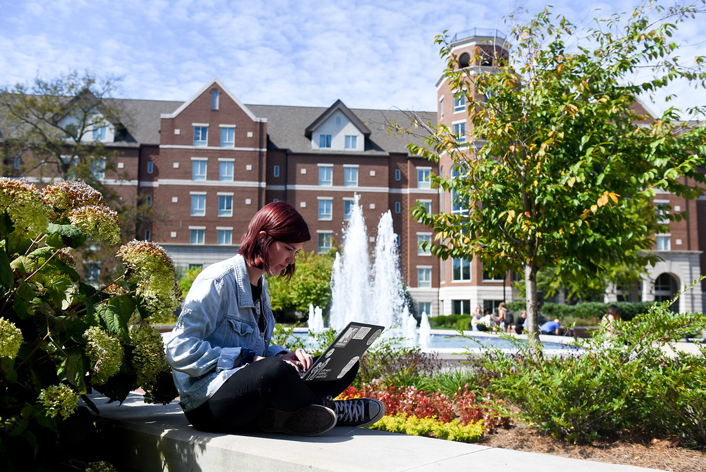 student sitting outside on campus working on a laptop