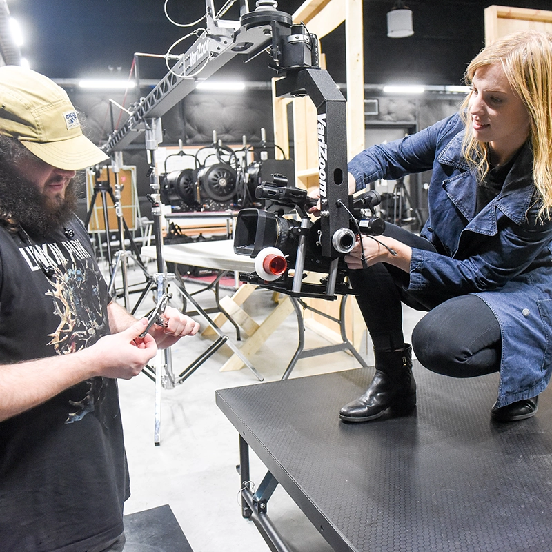 A male and female student setting up a camera in a classroom