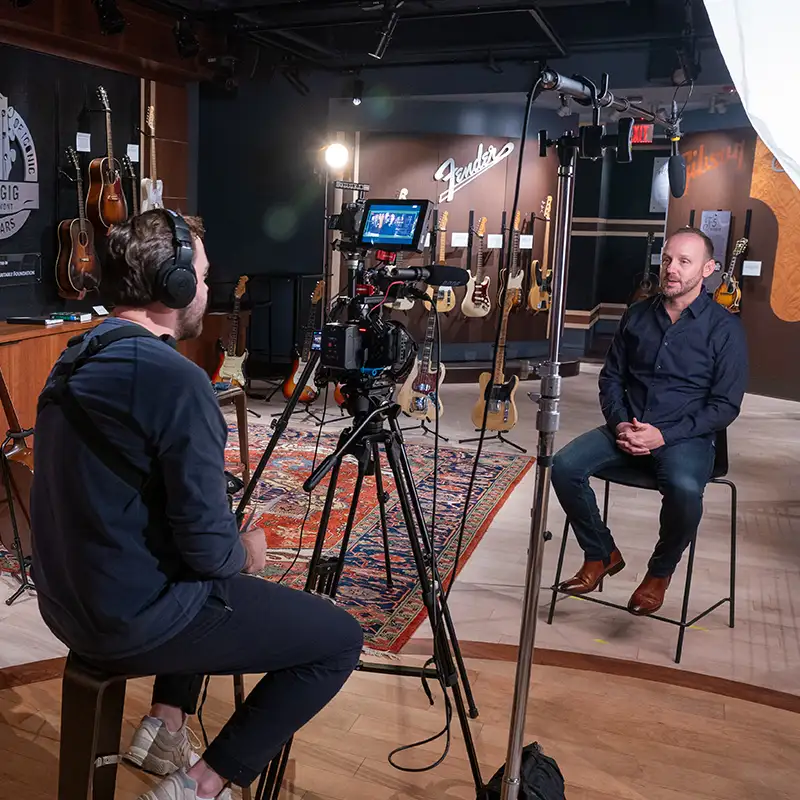 Student video interviewing a man in the Gallery of Iconic Guitars