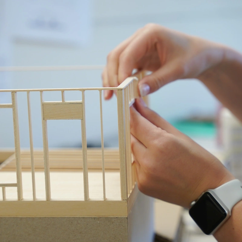 Close up of student building a small model building design