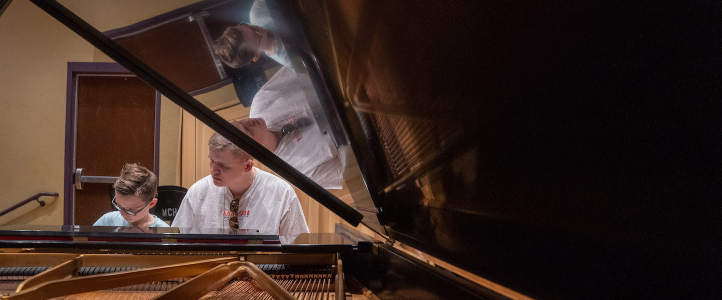 adult teaching a child to play the piano