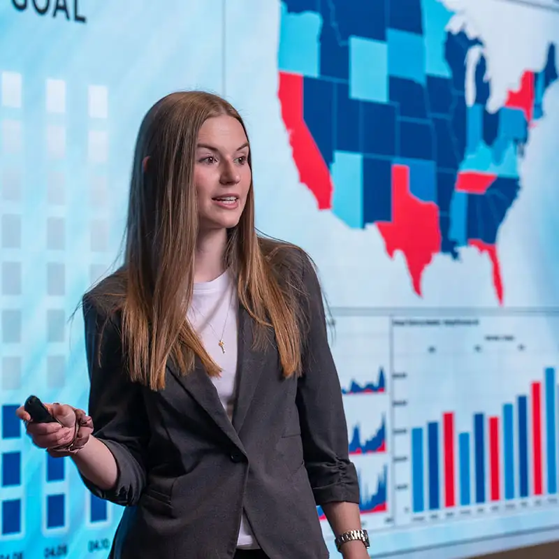 Student giving a presentation in front of an LED presentation wall