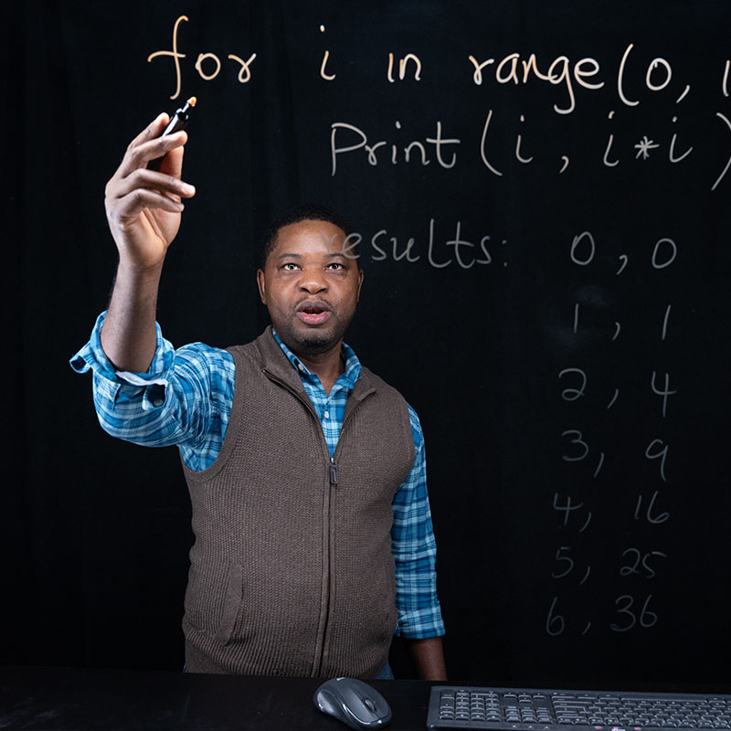 A student writing code on a glass wall