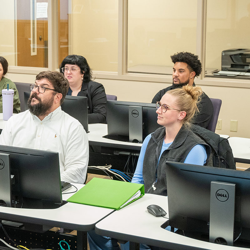 Graduate students in a computer lab discussing a topic