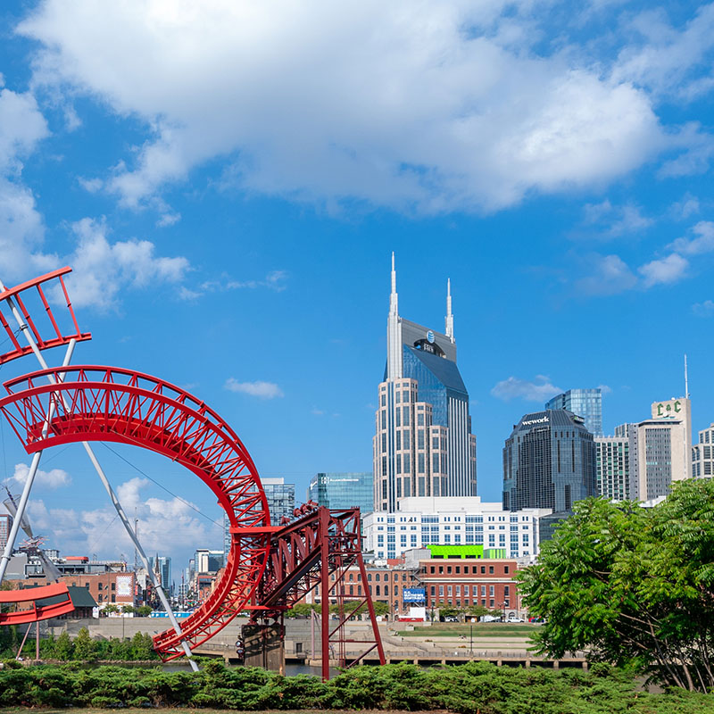 A scenic view of the Nashville skyline on a bright, sunny day, featuring the iconic AT&T Building and surrounding high-rises.