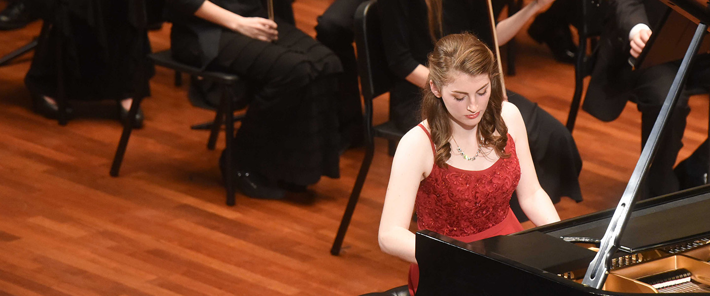 A female student plays a grand piano.