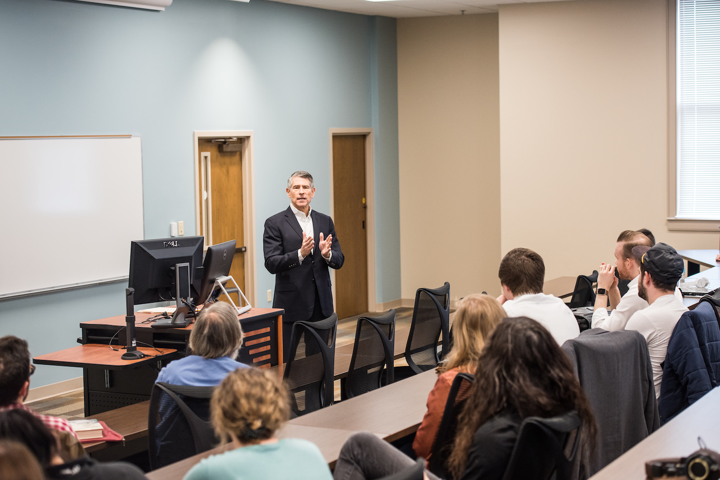 A speaker addresses a group of students at Belmont