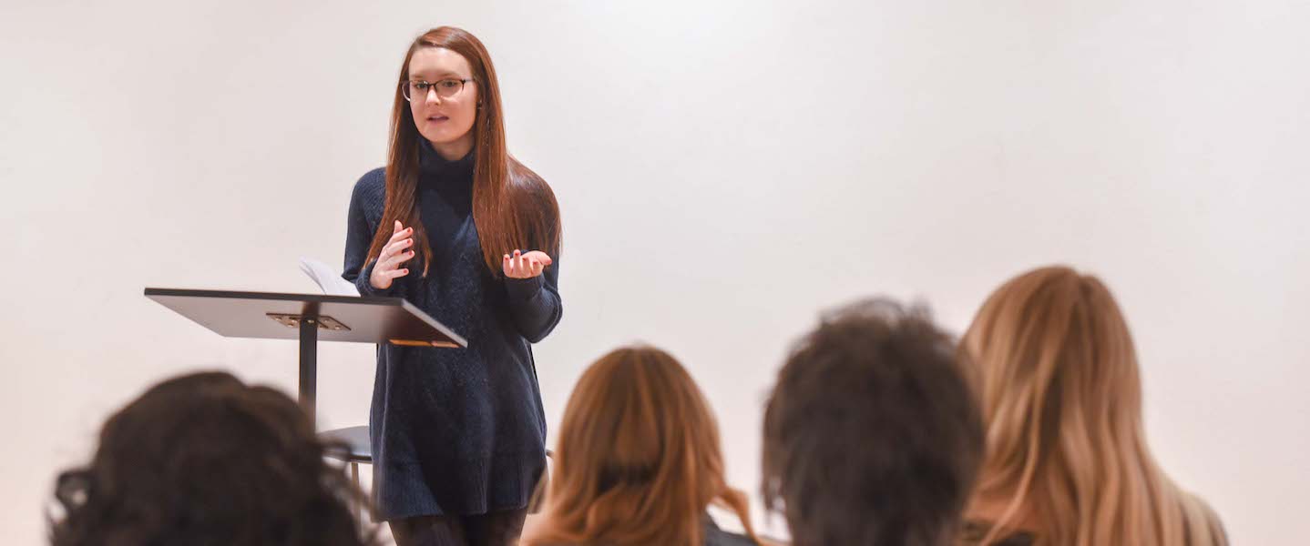 A speaker stands before students at a podium