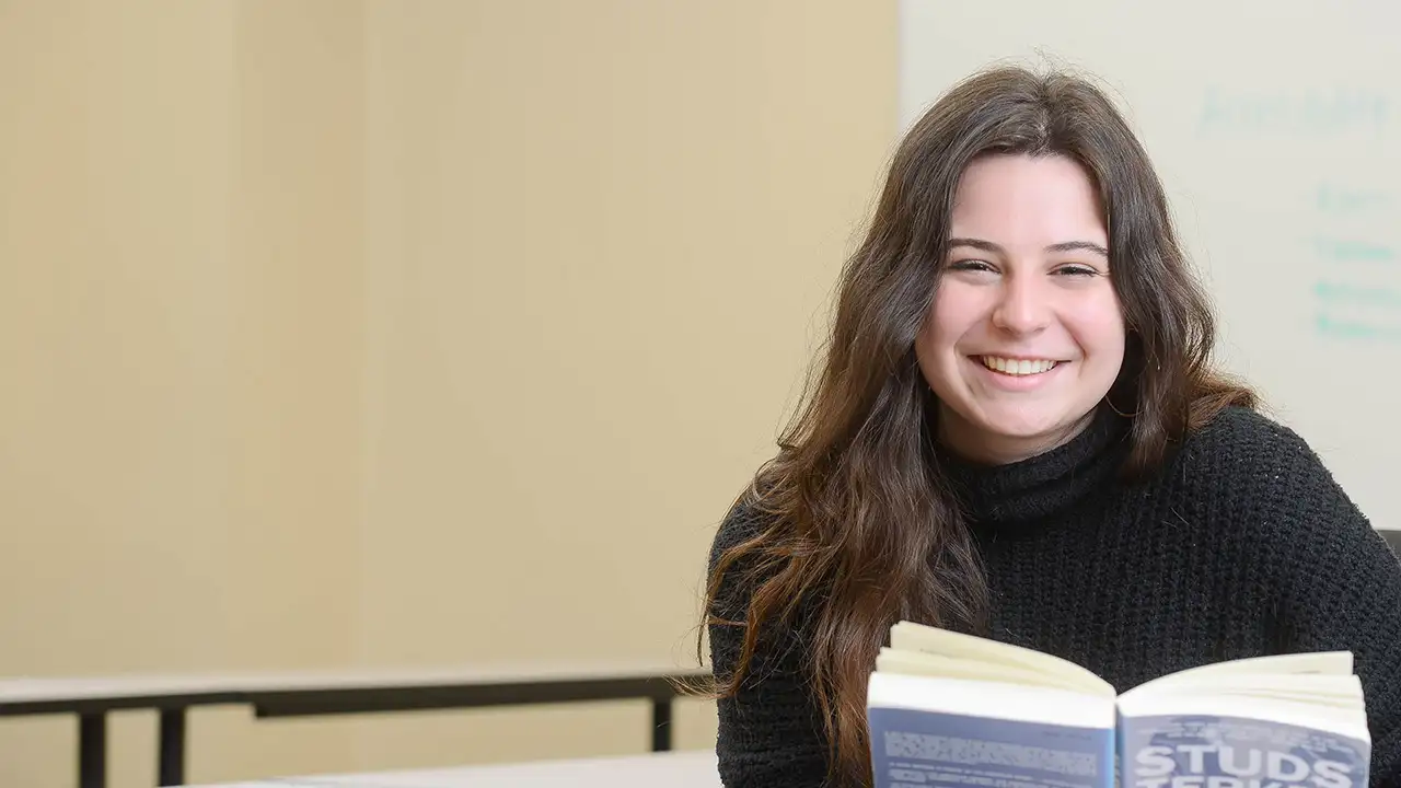 Rebecca Lewis reading a book in a classroom. 