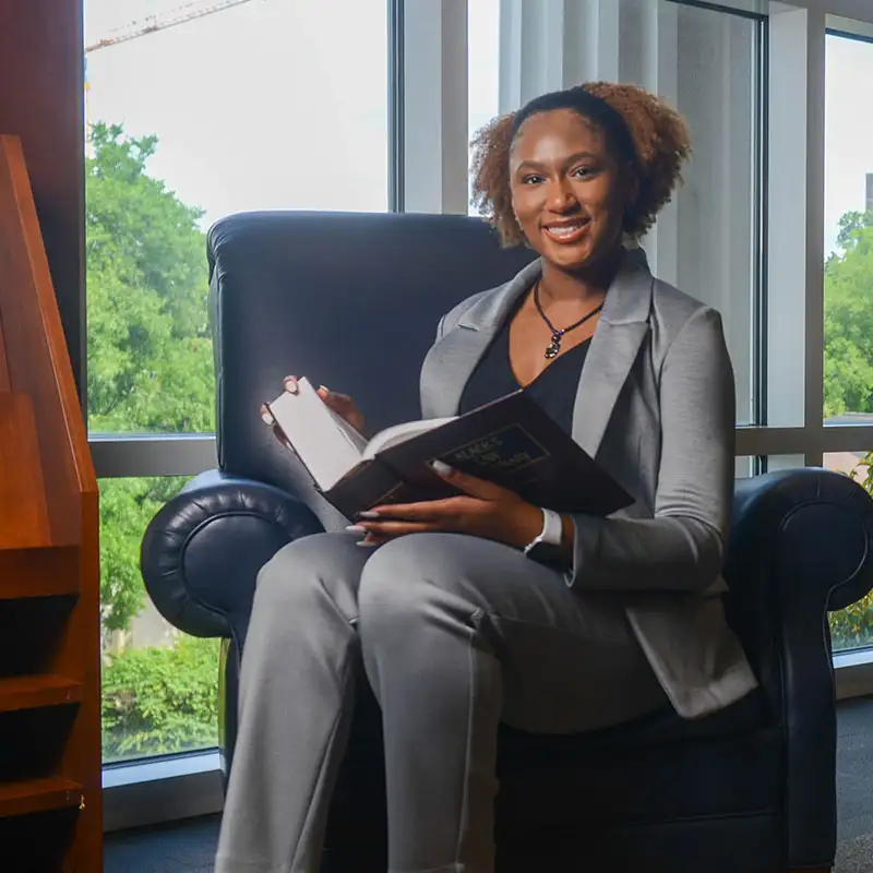 A graduate student sitting in a chair in the library