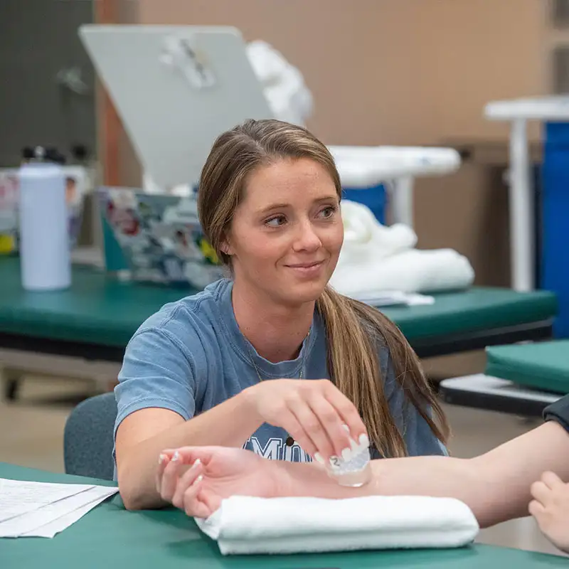 A student practicing first aid on another student in a health science class