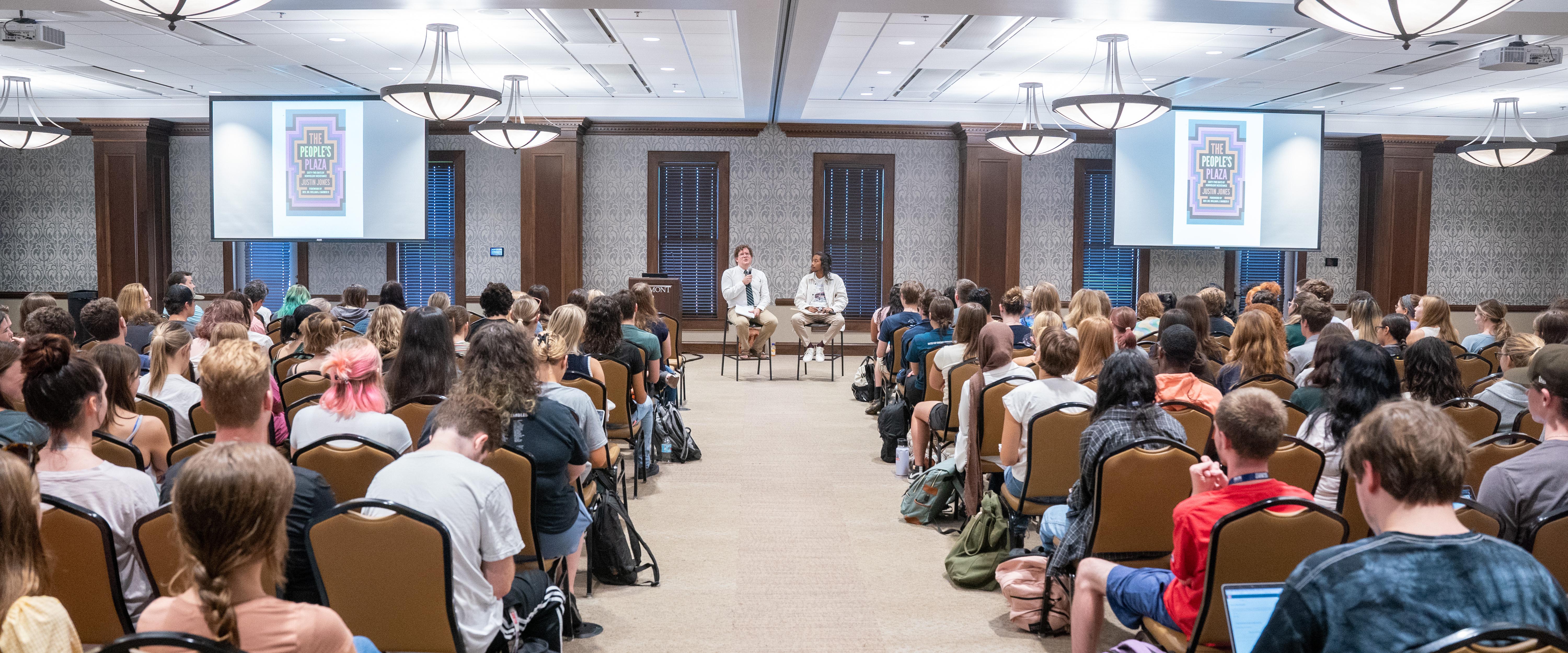 A group of students sitting in room while WELL Core speakers talks at event