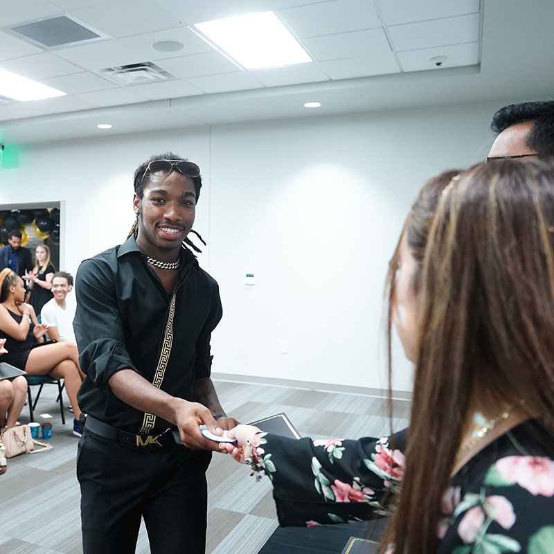 A student receiving his scholarship certificate at a Bell Tower Scholars event.