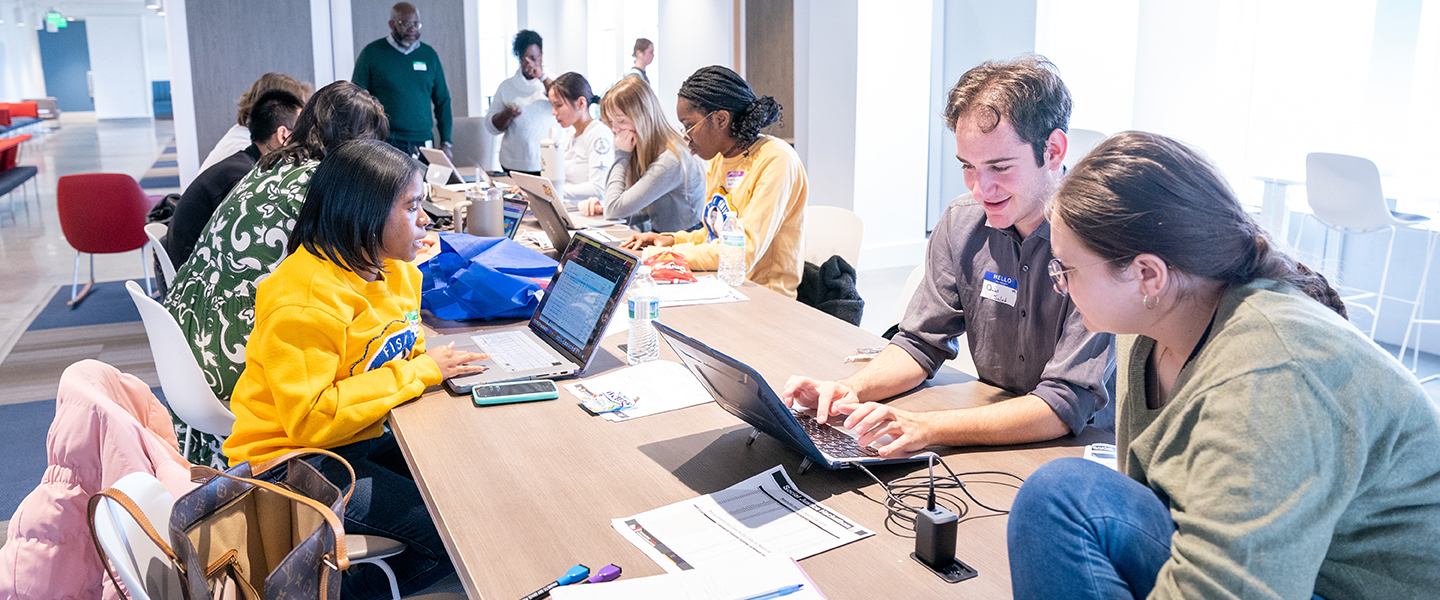 Students at a table working on their laptops.