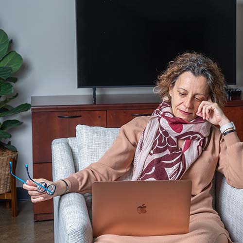 Female student thinks while on laptop sitting in a comfy chair