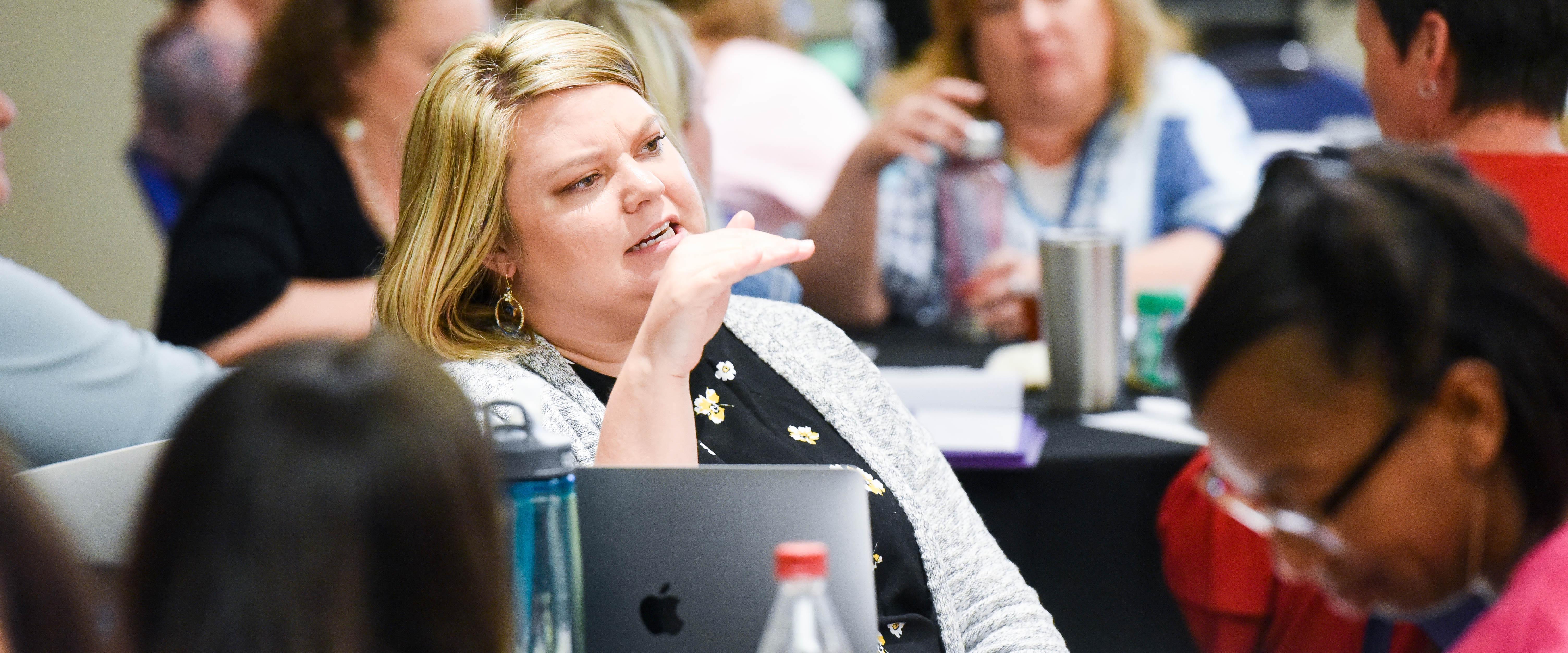 Graduate student participates in class discussion while sitting at table.