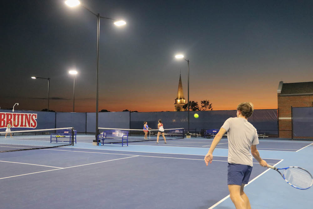 Students playing tennis on a tennis court