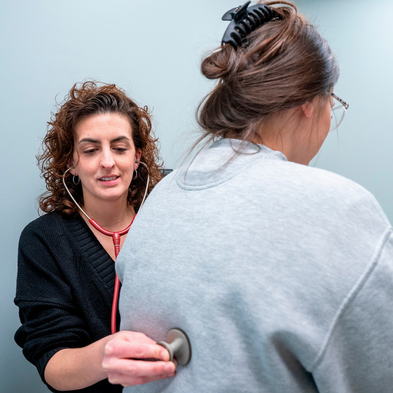 Provider giving a student a lung exam with a stethoscope