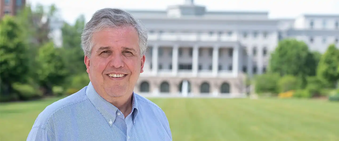 Greg Jones smiling as he stands with McWhorter Hall in the background