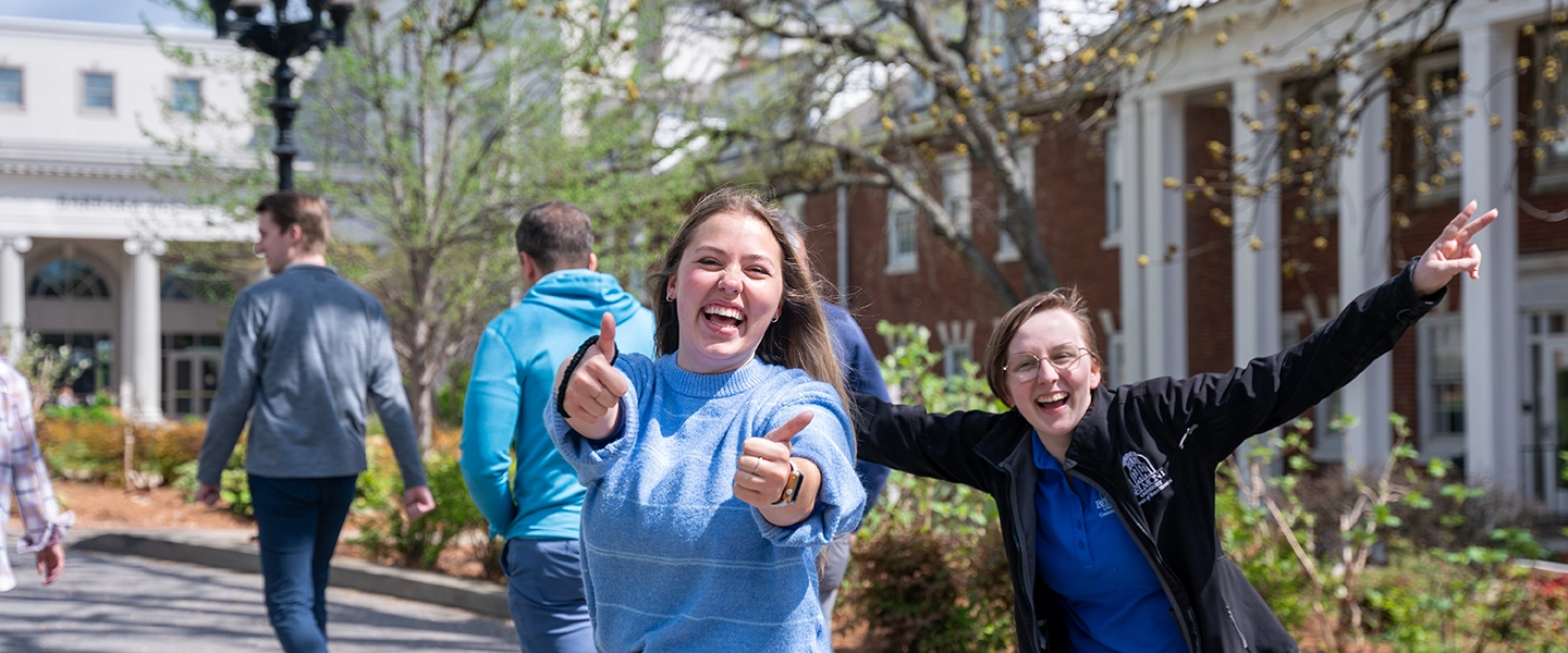 Belmont University staff on the campus grounds with campus buildings in the background