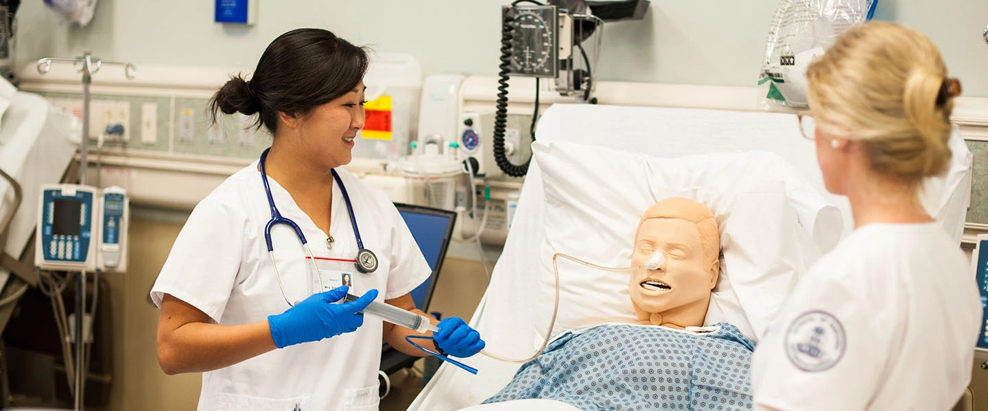 A nursing student smiles as she works in a nursing lab