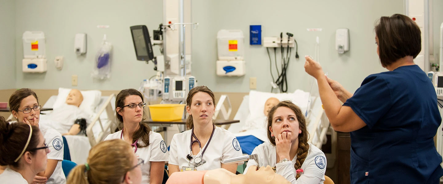 A professor demonstrating nursing skills during a lab