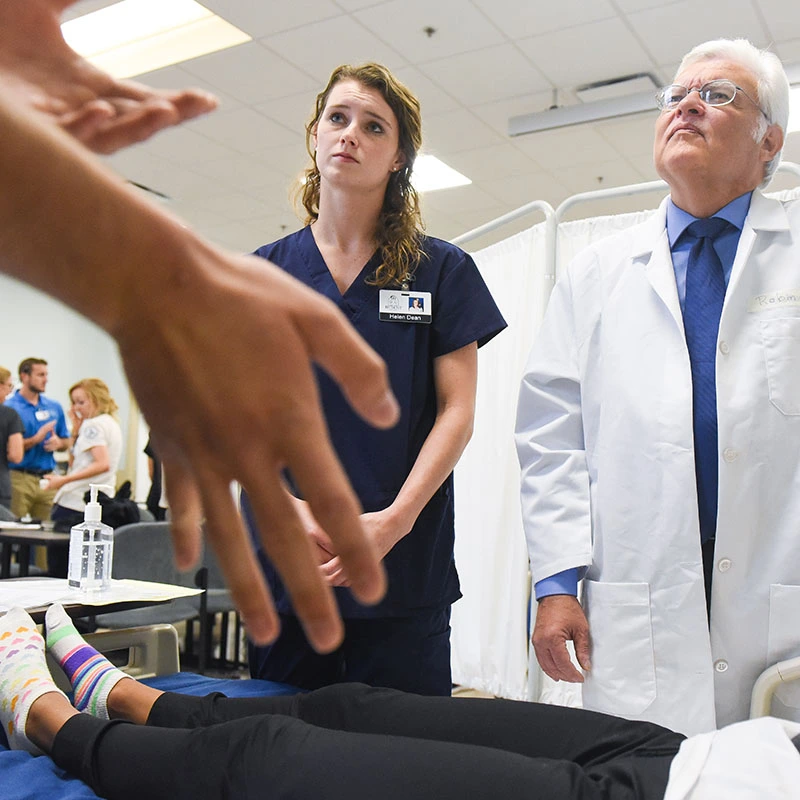 A student and a doctor talk with an actor during a live simulation