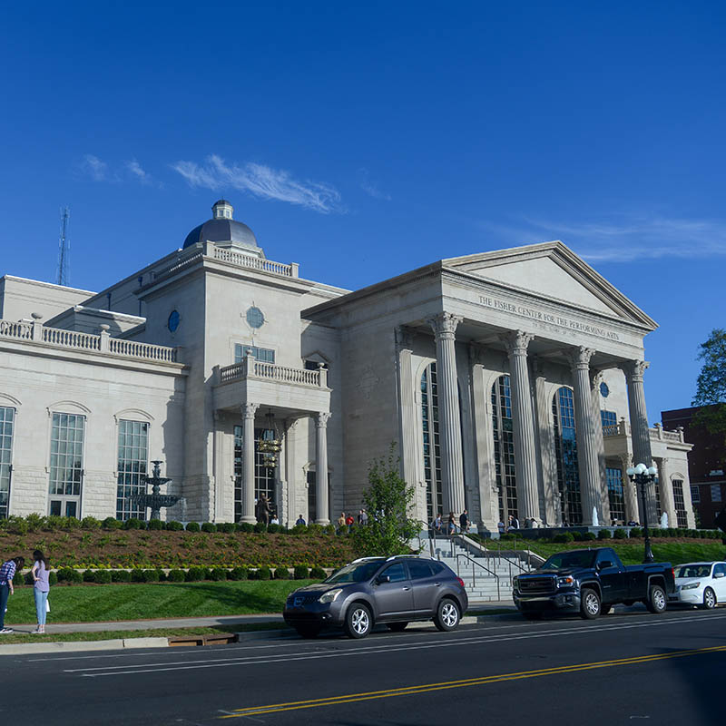 Outside of the Fisher Center for Performing Arts building on a sunny day.