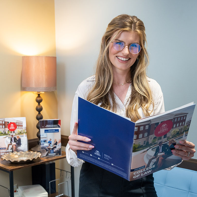 Prospective law student looking at the Law Viewbook and smiling