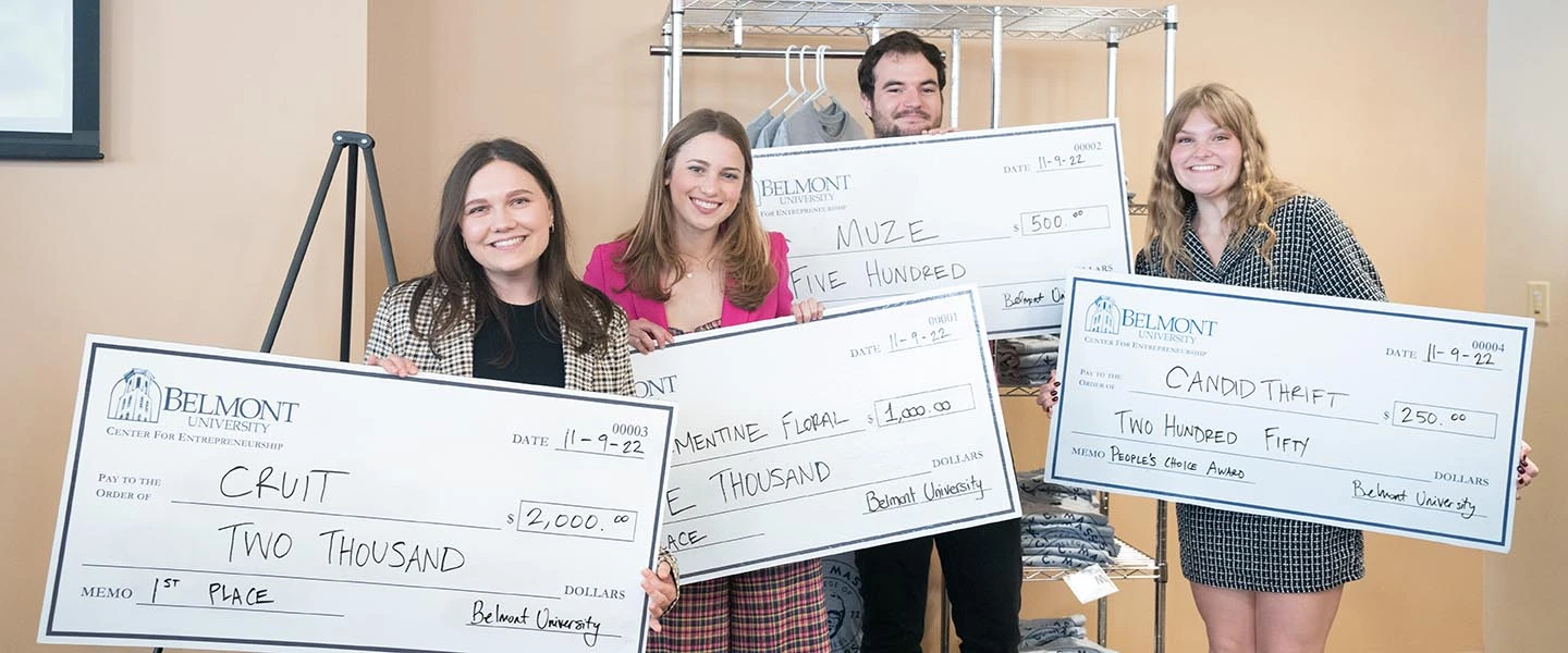 Student holding their check awards from the Business Pitch Competition