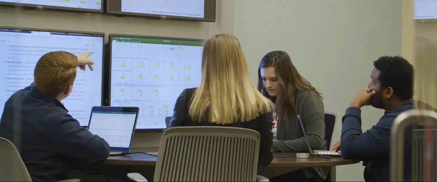 Students sitting at table studying spreadsheets