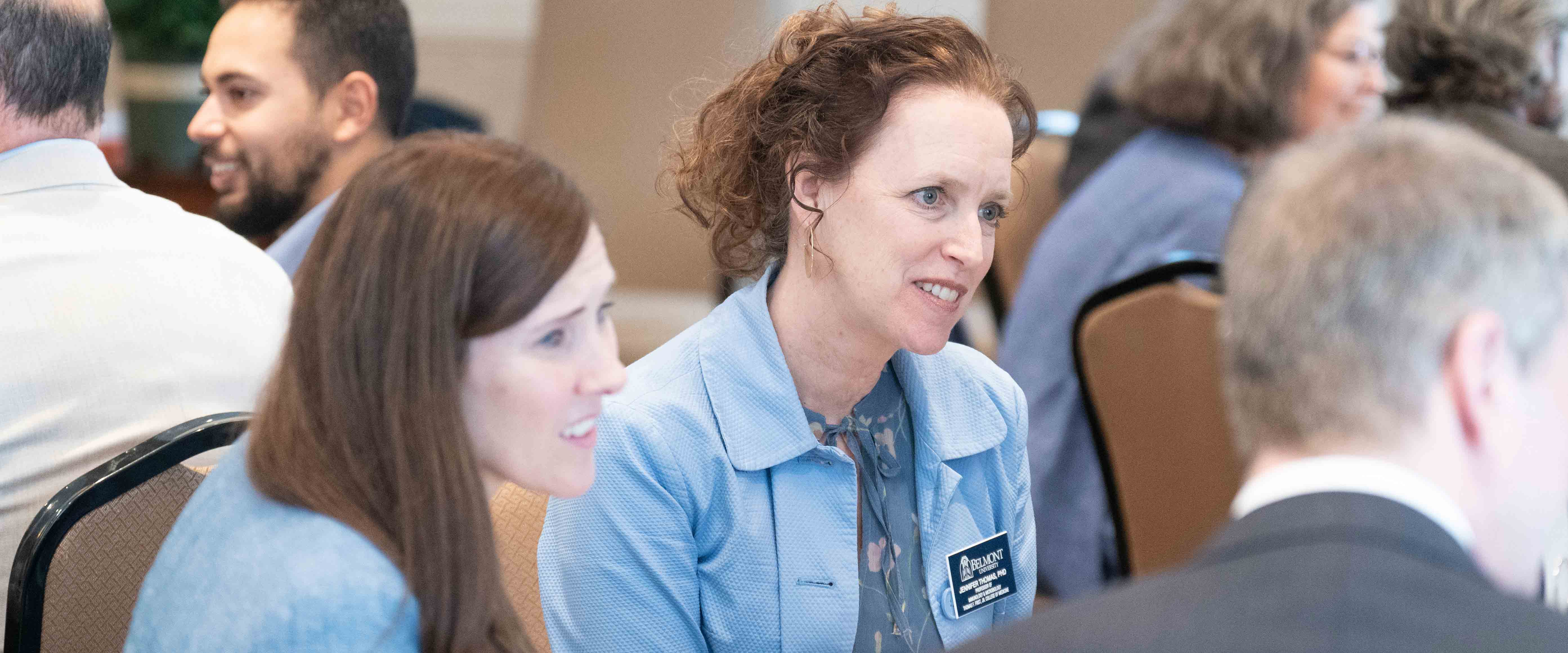 Medical school faculty have group discussion at table during luncheon event