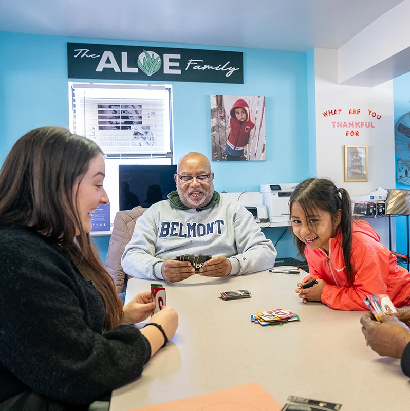 A child playing UNO cards with adults