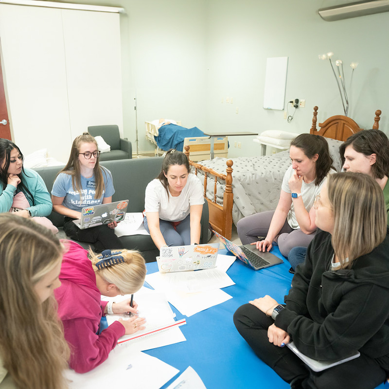 OT students sitting in a group working in a home health lab