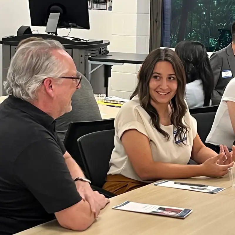 Professor sitting and talking to student at table in classroom