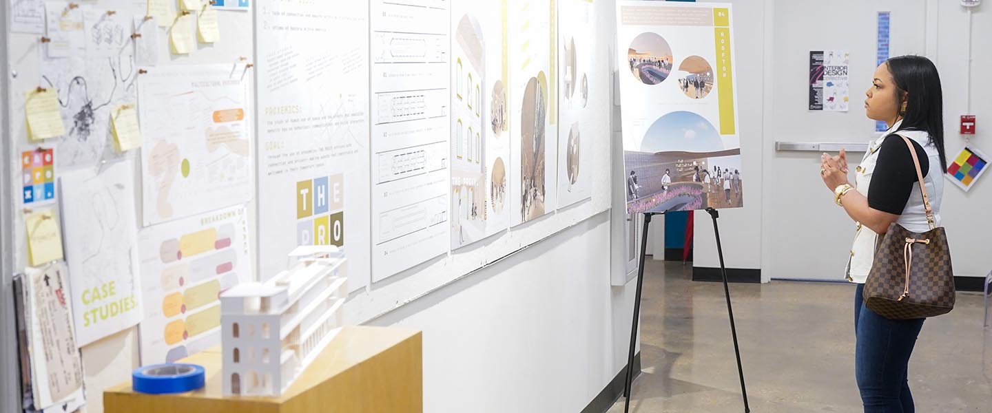 Woman looking at the design projects on the wall of the 2nd floor of Hitch