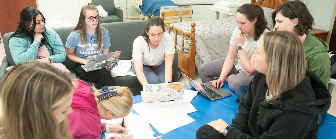 OT students sitting in a group working in a home health lab