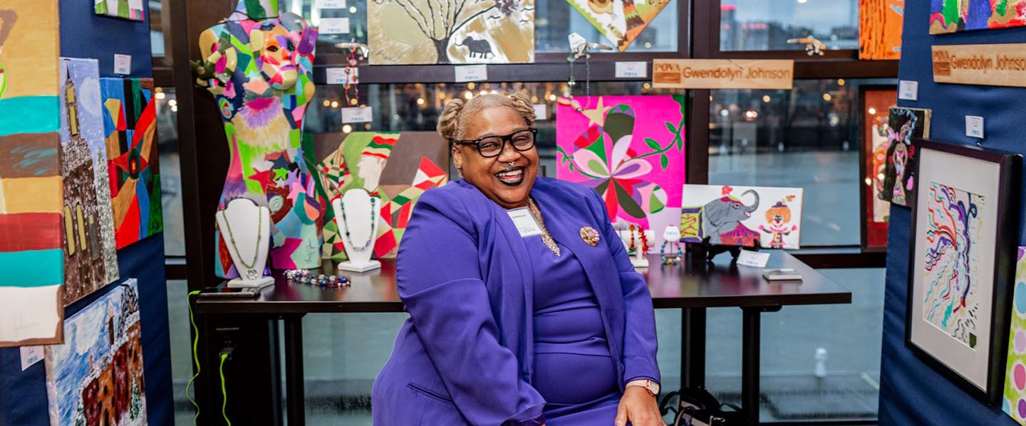 Woman sitting in front of her art booth at show