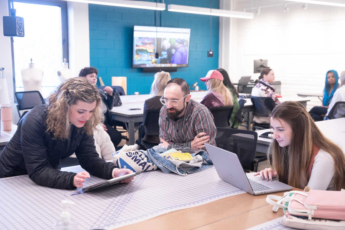 Fashion students have group discussion in class while sitting at tables