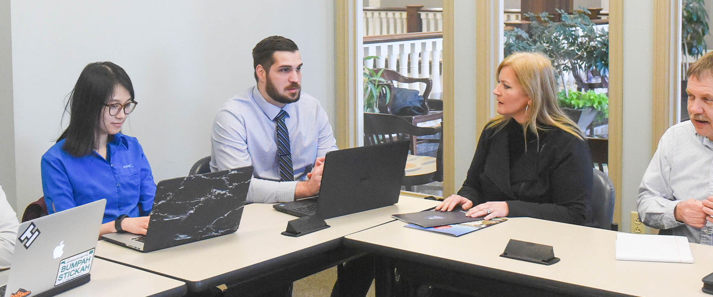 A small group of pharmacy students at a table with laptops.