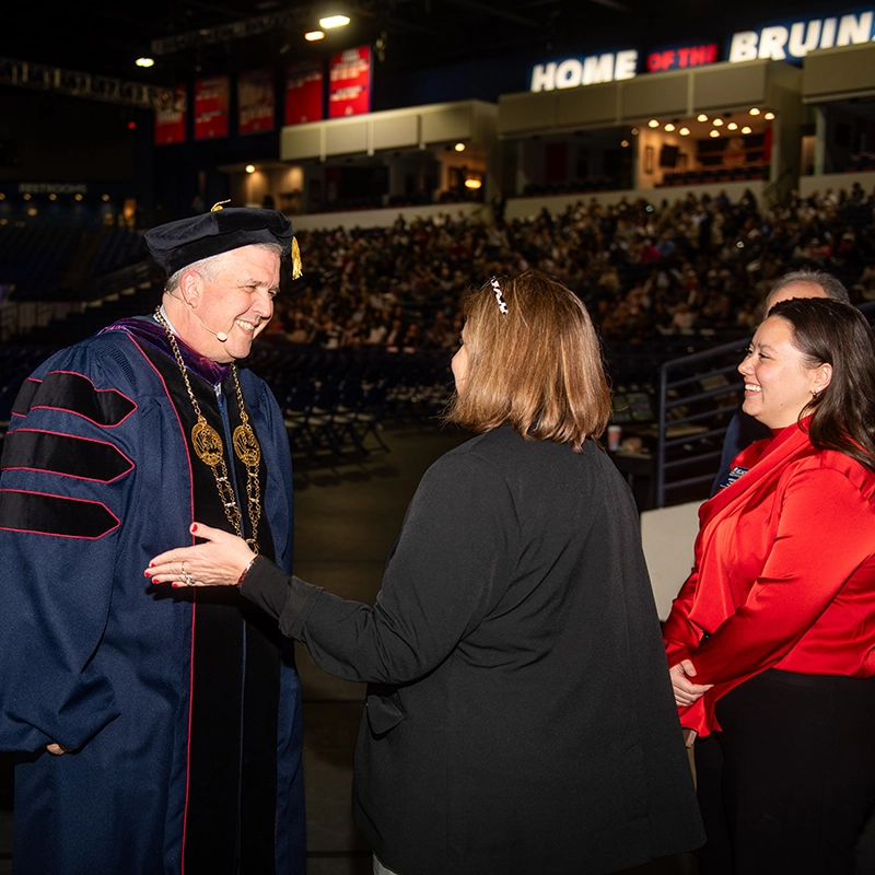 A Presidential Fellow greets university president Greg Jones during commencement