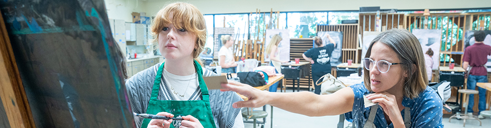 Art teacher instructing art student in class