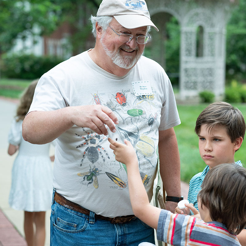 Dr. Murphree handing a bug in a bottle to a child